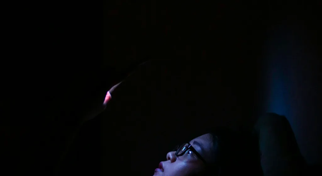 Person watching a screen in a dark room, retained as a general media-viewing illustration